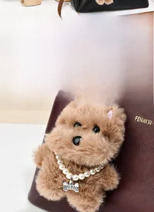 Plush brown dog charm with pearl necklace and metal bone tag on a red handbag