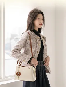Detail of elegant beige leather handbag with brown handles and heart-shaped charm accessory