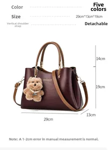 Detail view of dark red leather handbag with dimension markings and a cute bear charm