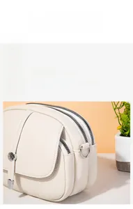 Close-up of cream litchi grain leather crossbody bag with triple zipper design details