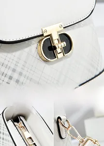 Detail view of the light gold twist lock and smooth metal zipper on white plaid handbag