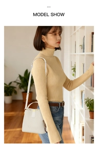 White embossed leather bucket bag with a cute bear charm shown in a cozy lifestyle setting