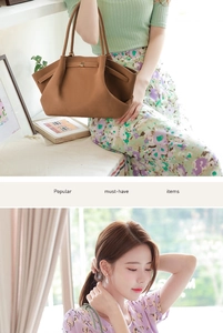 Close-up of brown leather tote bag with slim dual handles and metal buckle detail