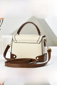 Detail view of cream white shoulder bag with brown leather trim and V-shaped stitching