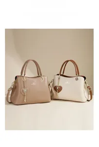 Detail of mocha brown and cream tote bags featuring a gold heart-shaped metal charm