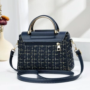Close-up of deep blue tweed handbag with gold thread texture and metal handle