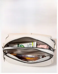 Interior view of beige leather crossbody bag with multiple compartments and zipper detail
