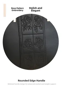 Detail of elegant black leather handbag featuring delicate rose embroidery and smooth handle