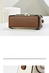 Close-up of leather box bag bottom with gold metal feet and refined contrast stitching