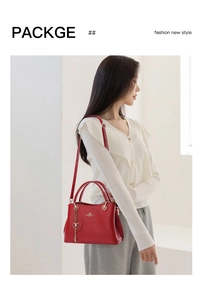 Detail of red leather tote bag showing heart pendant, strap, and texture on model