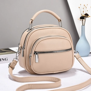 Minimalist beige pebble leather tote bag with triple zippers and adjustable shoulder strap