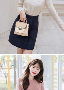 Close-up of color-block flap bag featuring a gold-tone rotary lock and textured grid fabric