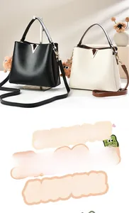 Detail of elegant PU leather bucket bags with gold V-hardware and plush charm accents