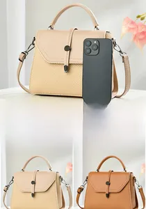 Detail view of the small crossbody messenger bag showing size comparison with a smartphone