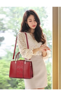 Elegant red leather handbag featuring detailed rose embossing and a stylish dual-handle design