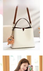 Detail of white PU leather bucket bag with contrast brown handle and V-shape metal buckle