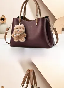 Detail of burgundy leather tote bag with gold hardware and plush bear keychain