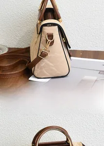 Détail de la texture en cuir plissé beige et de la poignée marron du sac à main