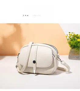 Detail of off-white lychee pattern leather crossbody bag with silver zippers and pockets