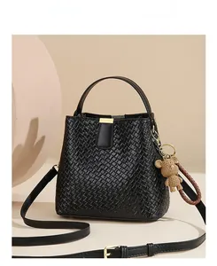 Front view of black woven leather bucket bag with top handle and bear charm detail