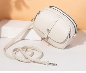 Detail of creamy white crossbody bag with lychee texture and double zipper closure