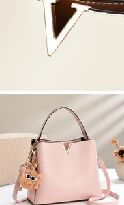 Detail of pink leather bucket bag with gold V-shaped logo and plush doll ornament
