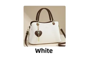 Detail of white tote bag featuring brown handles, gold hardware, and a heart pendant