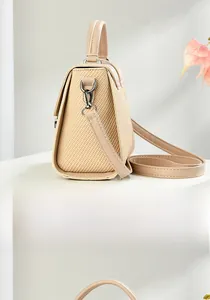 Detail view of woven side texture and smooth faux leather on beige messenger handbag