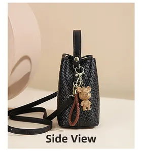 Side view of black woven bucket bag with cute bear pendant and adjustable strap