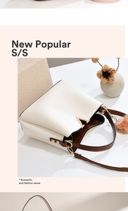 Macro view of cream PU leather bucket bag with gold V-hardware and brown plush charm