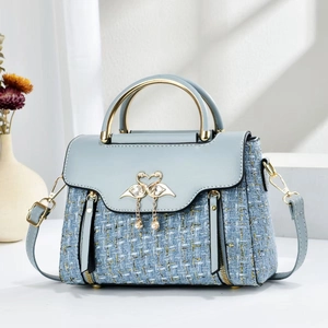 Detailed view of light blue tweed handbag with swan metal ornament and pearl tassels