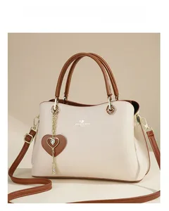 Detail view of the beige leather tote bag with heart charm and brand logo branding