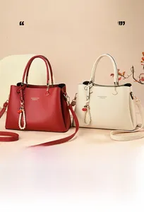 Detail of red and beige lychee leather tote bags with gold hardware and cherry charms