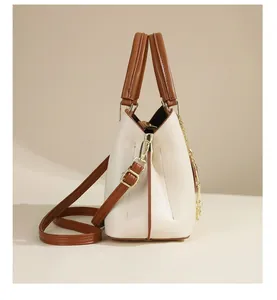 Side view of beige tote bag with brown contrast trim and elegant golden hardware