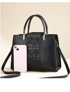 Detail of elegant black leather handbag with rose embroidery and gold hardware