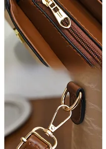 Détail de la fermeture éclair cœur doré et ferrures métalliques sur le sac en cuir marron