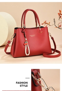 Detail of red textured leather tote with gold hardware and cherry pearl bag charm