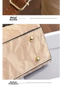 Détails de la boucle dorée et des clous de protection sur le sac plissé beige sous le bras