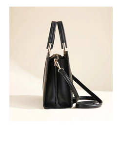 Side view of structured black leather handbag with accordion pleats and gold hardware