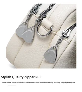 Macro shot of silver textured zipper pullers and D-ring on cream pebble leather bag