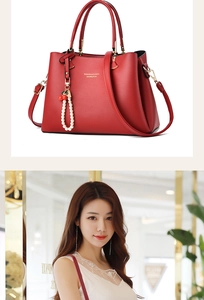 Detail of red lychee grain leather handbag with pearl cherry charm and metal lettering