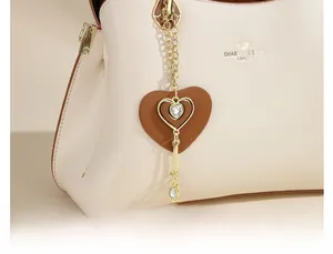 Close-up of beige leather tote with heart pendant detail and embossed texture