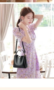 Close-up of black leather bucket bag with gold V-buckle and cute brown plush bear charm