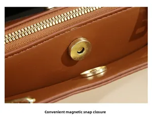 Close-up of brown leather bag showing gold zipper and secure magnetic snap closure detail