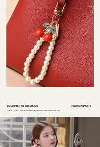 Detail of red lychee grain leather handbag with a handmade pearl cherry bag charm accessory