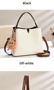 Detail of cream white bucket bag with brown straps and plush sunglasses charm accessory