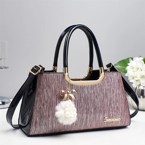 Détail du tissu rose scintillant et cuir verni noir sur sac à main avec breloque