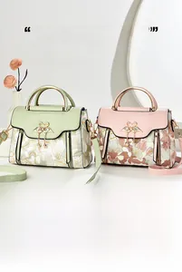 Detailed view of floral tote bag with swan clasp and pearl tassel in pink and green