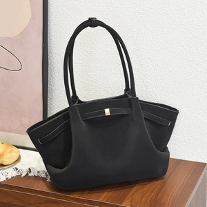 Large capacity black fashion tote bag with gold metal accents on a stylish wooden surface