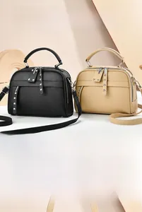 Close-up of litchi grain leather texture and dual zipper detail on stylish handbags